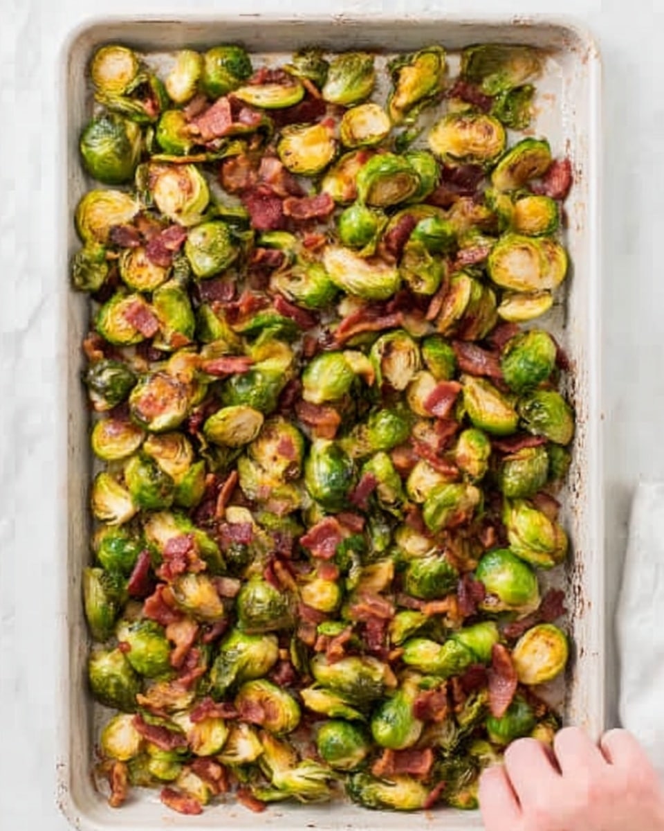 A large white baking tray filled with roasted Brussels sprouts and crispy bacon pieces scattered evenly across the tray. The Brussels sprouts are halved, showing vibrant green outer leaves with some golden brown crisped edges, mixed with rich reddish-brown bacon bits. The tray sits on a white marbled surface, and a woman's hand is reaching in from the right side, about to grab some of the food. photo taken with an iphone --ar 4:5 --v 7