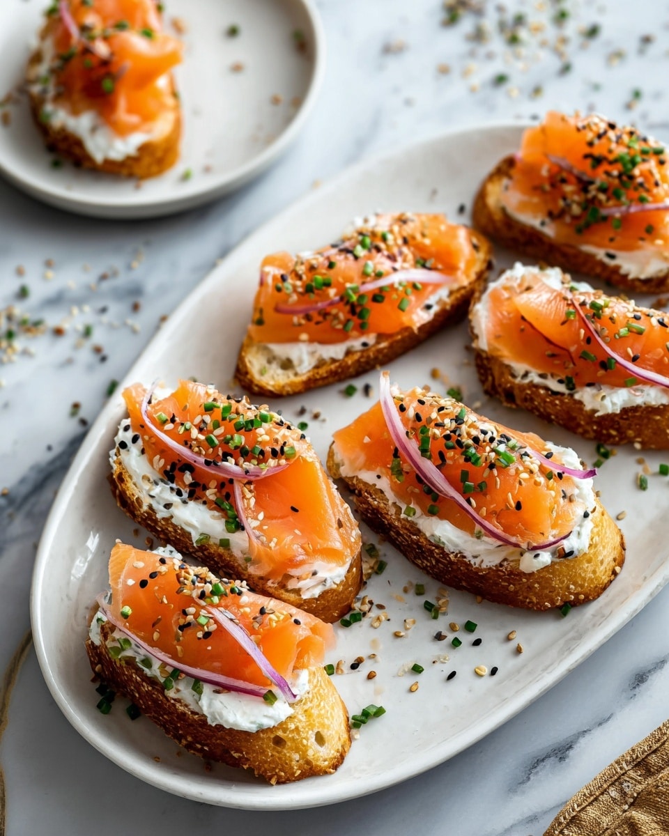 A white oval plate holds seven pieces of toasted bread, each layered with a thick spread of white cream cheese, topped with bright orange slices of smoked salmon. Thin, curved slices of purple-red onion rest over the salmon, adding contrast. The toasts are sprinkled with small black and white sesame seeds and finely chopped green chives. In the background, there is a smaller part of a white plate with one piece of the same toast. The whole scene is set on a white marbled surface with some scattered seeds and chives around. Photo taken with an iphone --ar 4:5 --v 7
