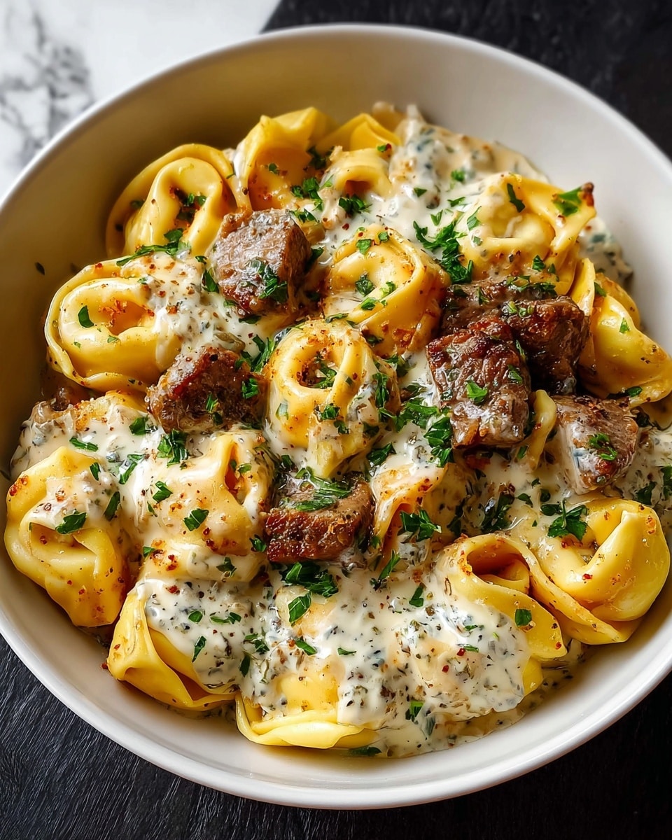 A close-up view of a black bowl filled with two layers: the bottom layer is golden yellow tortellini pasta with soft texture and slight browning on edges, while the top layer has browned chunks of cooked meat mixed with creamy white sauce that has green herb flecks, all sprinkled with chopped green herbs and black pepper. The bowl sits on a white marbled surface with some green blurred in the background. photo taken with an iphone --ar 4:5 --v 7