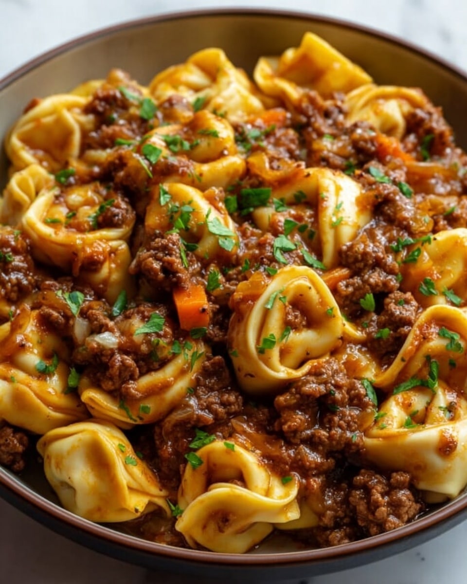 A close-up of a bowl filled with cooked tortellini pasta mixed with a rich meat sauce. The tortellini are golden yellow with a smooth texture, folded tightly in multiple layers holding the filling inside. The meat sauce is thick and chunky, dark brown with visible pieces of cooked ground meat and small orange bits of carrot. There are small bits of translucent cooked onion scattered throughout, adding texture. On top, bright green chopped fresh herbs are sprinkled evenly, giving a fresh contrast. The dish is placed on a white marbled surface. photo taken with an iphone --ar 4:5 --v 7